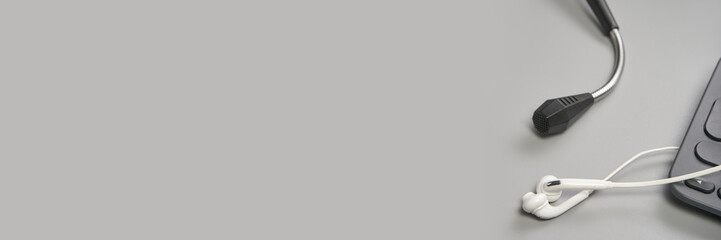 Podcast record. Microphone and white headphone. Grey monochrome. Audiobook and podcasting. Audio technology. Home school teaching. Horizontal banner with copyspace