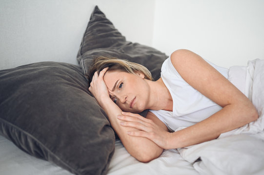 Depressed woman tormented by restless sleep, she is exhausted and suffering from insomnia, bad dreams or nightmares, psychological problems. Inconvenient uncomfortable bed or mattress. Lack of sleep