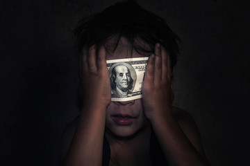 Child homeless, beggar closes his eyes with a dollar bill (the concept: money obscures the truth,...