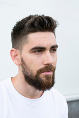 Portrait of a very handsome Caucasian man with a beard and white shirt.