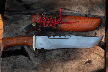 Large knife in leather and natural wood grain casing on table background handmade fo Thailand