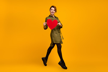 Fototapeta na wymiar Full length body size view of her she nice-looking attractive lovely pretty lovable cheerful cheery girl going holding in hand red heart isolated on bright vivid shine vibrant yellow color background