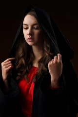 Portrait of a pretty girl in a black Cape with a hood