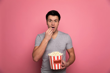 Watching a blockbuster. Close-up photo of a young man in a gray t-shirt, who is eating popcorn,...