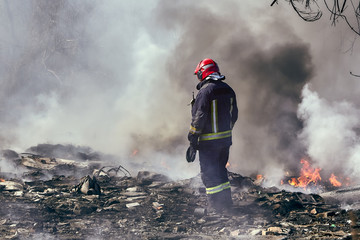  firefighter in extinguishing the fire on the illegal dump