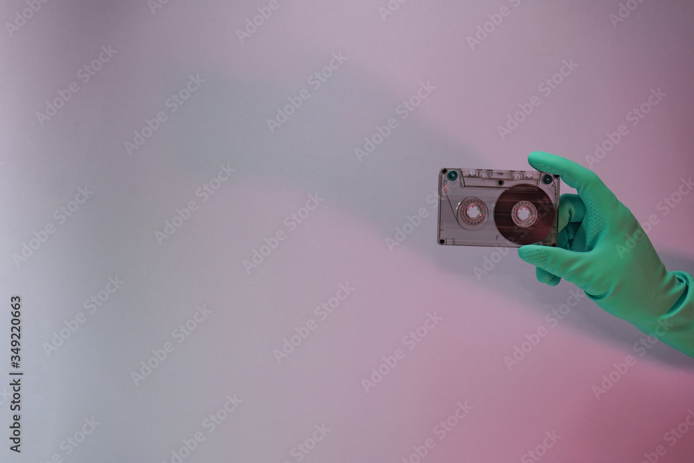 Poster Green Hand holding audio cassette tape in the color light. Beautiful minimal in neon light. Minimalism retro style concept. Background pattern for design.