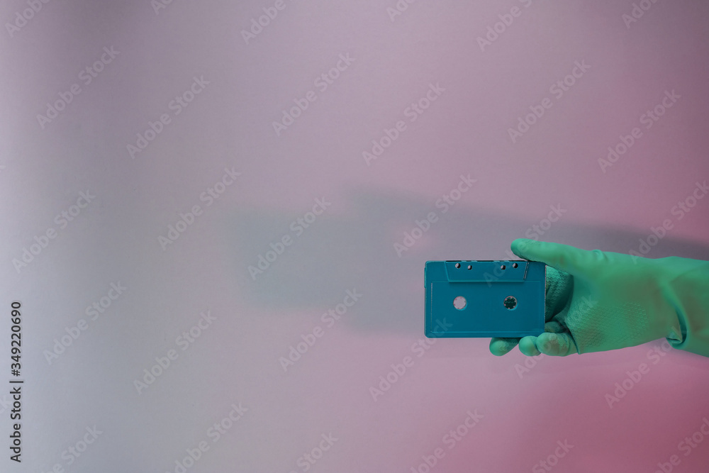 Poster Green Hand holding audio cassette tape in the color light. Beautiful minimal in neon light. Minimalism retro style concept. Background pattern for design.
