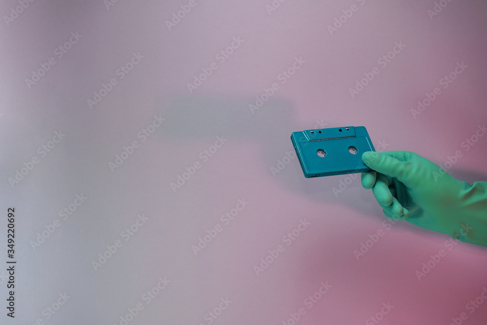 Poster green hand holding audio cassette tape in the color light. beautiful minimal in neon light. minimali
