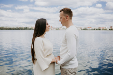 A man and a pregnant woman near the lake