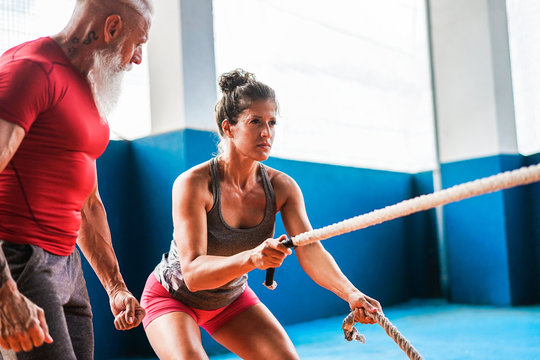 Fit woman with battle rope inside garage - Coach motivating female athlete during Coronavirus time for personal gym class - Workout and sport concept - Focus on female face