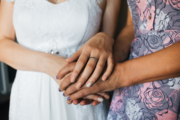 mother holds her daughter bride by the hands on the wedding day