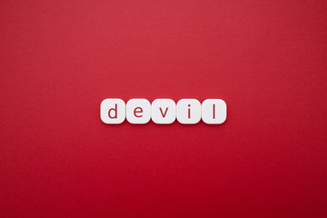 Alphabet devil word block with red background.