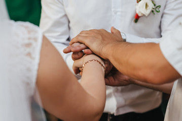 hands of the bride and groom and the Holy father at the wedding ceremony