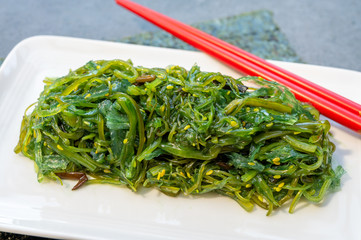 Green fresh oriental seaweed salad served with chopsticks