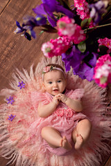 happy cute girl 3-5 months old lies on her back with flowers. Mothers Day. International Women's Day.