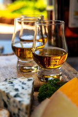 Whiskey and cheese pairing, tasting whisky glasses and plate with sliced cheeses
