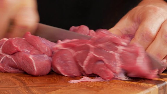 man cuts meat with a knife on a cutting board