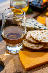 Whiskey and cheese pairing, tasting whisky glasses and plate with sliced cheeses