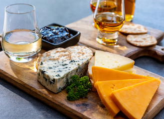Whiskey and cheese pairing, tasting whisky glasses and plate with sliced cheeses