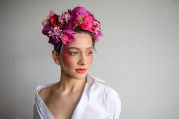Naklejka premium Sensual woman in floral wreath. Portrait of beautiful young woman with red lips dressed in a white blouse.