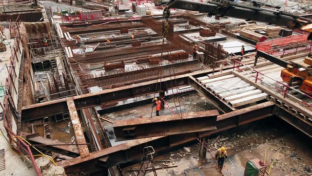 Mega Construction site in downtown Hong Kong with workers and Metal beam lifting operation, closeup aerial view.