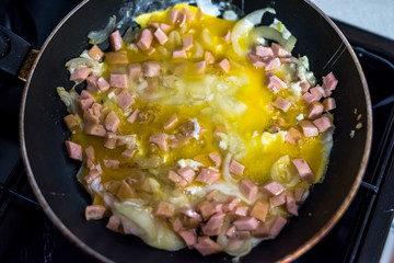 freshly fried egg with sausage and onion in a frying pan