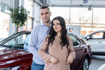 Fototapeta na wymiar Happy couple posing with new cars in showroom