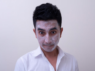 Asian handsome young man applying cream at his face with smiley face, Skin care concept