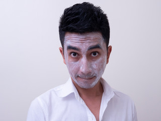 Asian handsome young man applying cream at his face with smiley face, Skin care concept