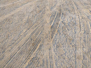 Background of car wheel tracks in the sand. Tire marks in sand close up.