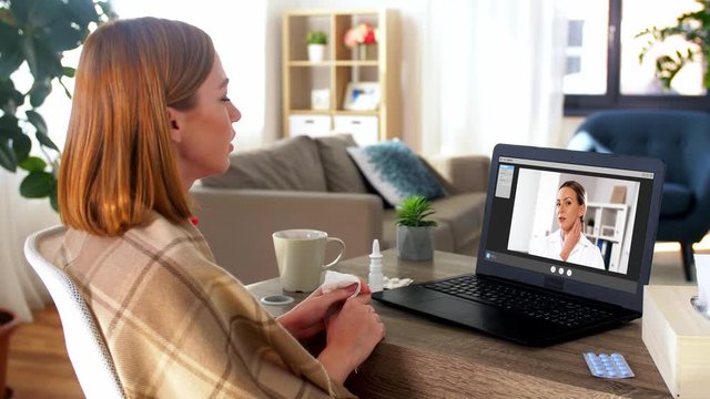 medicine, healthcare and technology concept - sick young woman having video call or online consultation with doctor on laptop computer at home