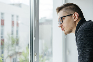 A man with glasses looks out the window