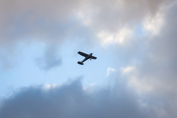 Small plane flying on the backgorund of clouds. Photo taken in cloudy day, Europe, Latvia.