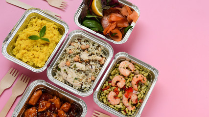 Fototapeta na wymiar Healthy food restaurant dish delivery. Take away of fitness meal. Weight loss nutrition in foil boxes. Top view on pink background. service food order online delivery. airline meals and snacks