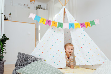 Little boy in a hut with stay at home flag garland across © zzzdim