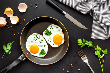 Fried eggs on frying pan on black desk top-down