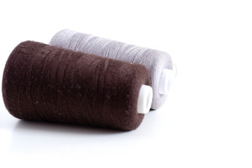Brown and gray threads on a white background. Sewing supplies
