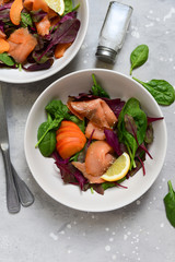 salmon salad with apricot, spinach, arugula, sesame and lemon. dish for a healthy lunch or dinner. menu healthy food delivery. Top view with copy space.