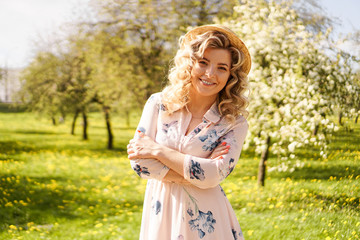 Smiling summer woman with straw hat in park - apple garden in spring sunny day
