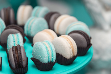 Light cream, tiffany blue and chocolate macaroons on tiffany blue stand. Food knolling concept - obrazy, fototapety, plakaty