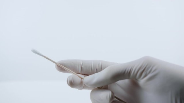 Holding swab for coronavirus testing. Nurse with white medical gloves.