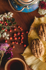 Still life of cup of tea, flowers and berries on the wooden board.