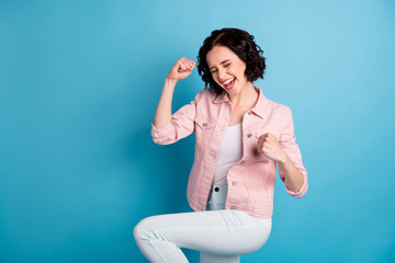 Photo of beautiful crazy lady short black hairdo raise hands fists celebrating winning match game football team supporter wear casual pink jacket pants isolated blue color background