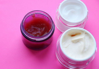 three glass jars with cream for the body, face, on a bright pink background. Cream texture. Home care, care, cosmetics. Natural cream, affordable care.