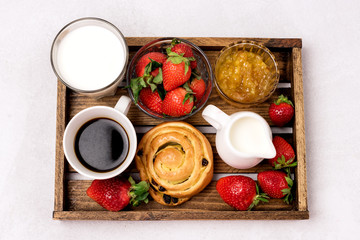 Wooden Tray with Breakfast Freshly Baked Buns with Raisins and Cinnamon Cup of Black Coffee Cream Ripe Strawberry and Orange Jam in Glass Bowl