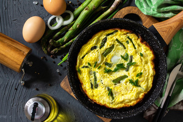 Healthy Asparagus Omelet. Egg omelet with asparagus and onions in a cast iron skillet on a stone...