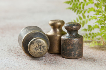 Three antique bronze weights for scales on concrete background.