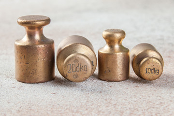 Four antique bronze weights for scales on concrete background.