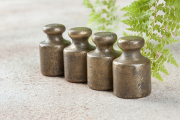 Four antique bronze weights for scales on concrete background.