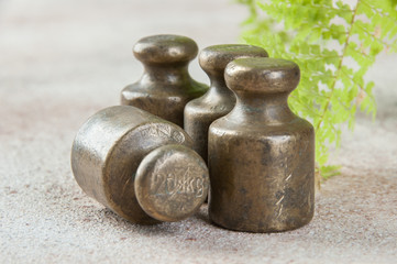 Four antique bronze weights for scales on concrete background.